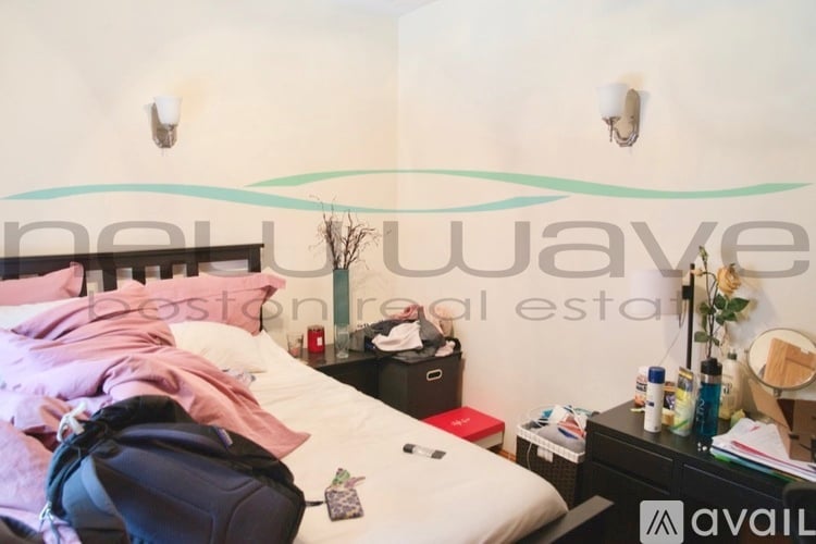 A bedroom with a bed, nightstand, and a backpack on the bed.
