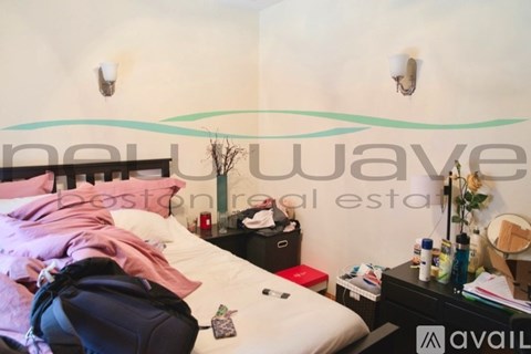 A bedroom with a bed, nightstand, and a backpack on the bed.