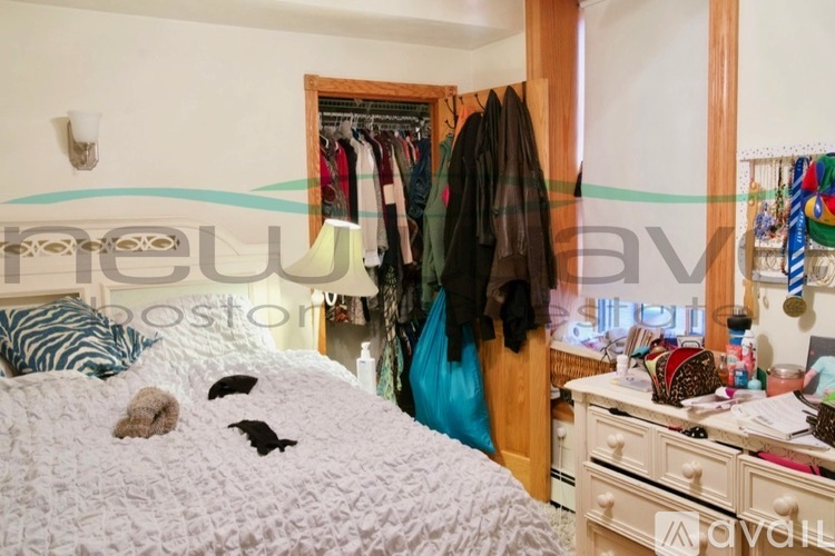 A bedroom with a white bedspread and a white dresser with a mirror above it.