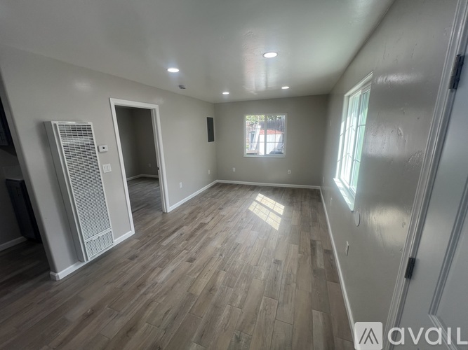 A room with wooden flooring and a window letting in natural light.