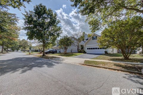A house with a driveway and trees in front of it.
