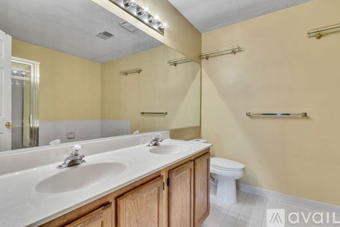 A bathroom with a toilet, two sinks and a mirror.