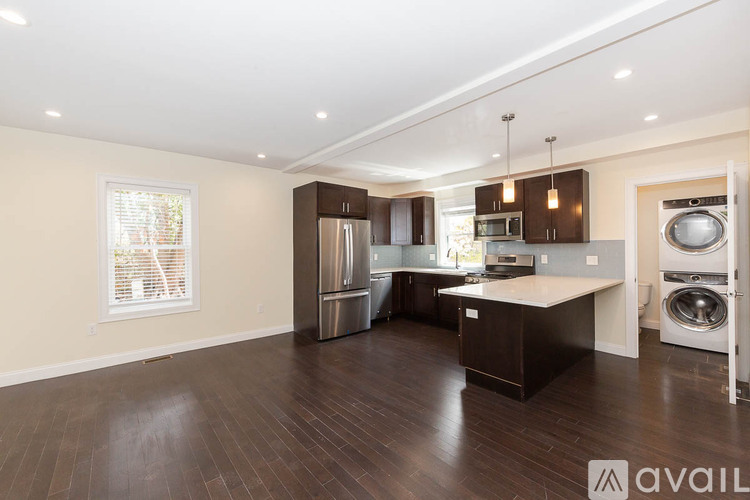 A spacious kitchen with dark wood floors and modern appliances.