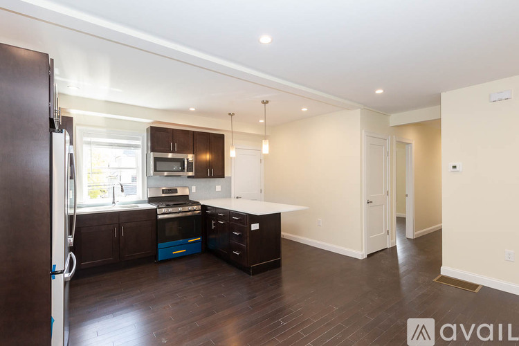 A kitchen with dark wood floors and white walls.