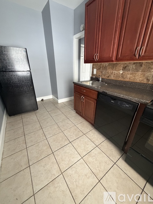 A kitchen with brown cabinets and a black refrigerator.