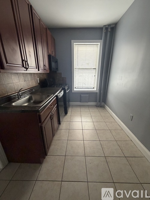 A kitchen with brown cabinets and a window with blinds.
