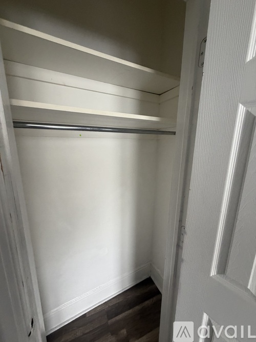 A white door with a white wall and a white shelf above it.