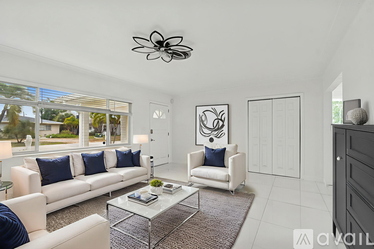 A living room with a white couch, a coffee table, and a large window.