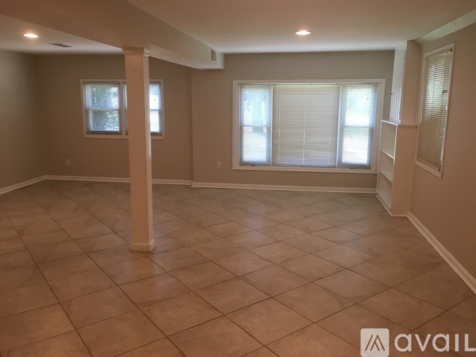 A spacious room with tiled flooring and three windows.