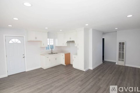A spacious kitchen with white cabinets and a wooden island.