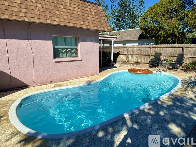 A small pink house with a pool in the backyard.