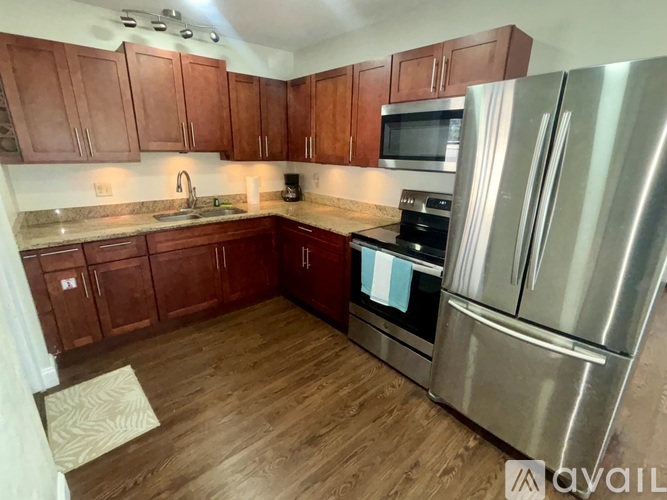 A kitchen with wooden cabinets and a stainless steel refrigerator.