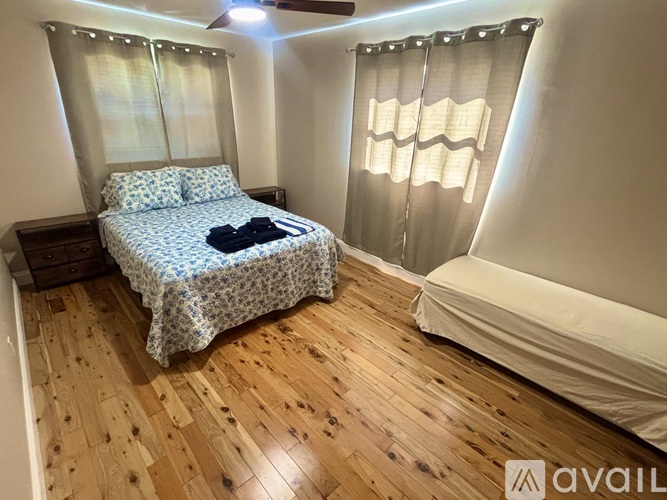 A bedroom with a bed covered in a blue and white patterned bedspread and a wooden floor.