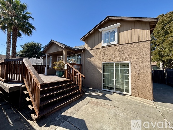 A house with a wooden deck and a palm tree in the background.