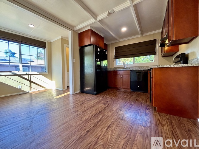 A kitchen with wooden floors and a black refrigerator.