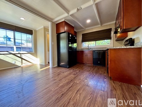 A kitchen with wooden floors and a black refrigerator.