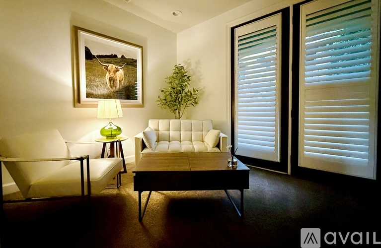 A dining room with a table, chairs, and a painting on the wall.