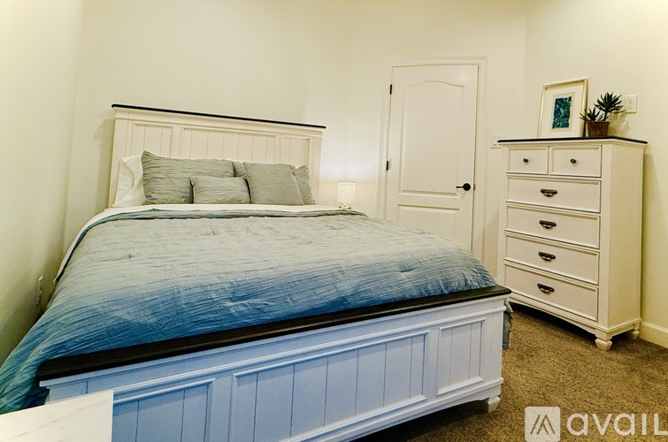 A bedroom with a bed, nightstand, and carpet.