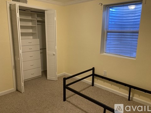 A room with a white closet, a window with blinds, and a carpeted floor.