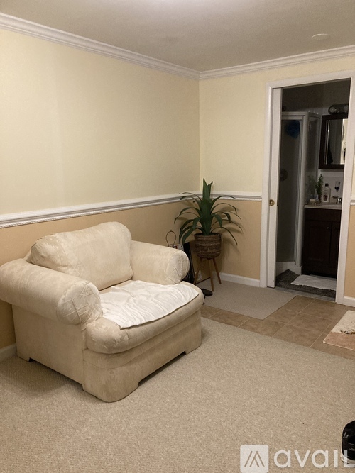 A white couch in a room with a doorway leading to a kitchen.