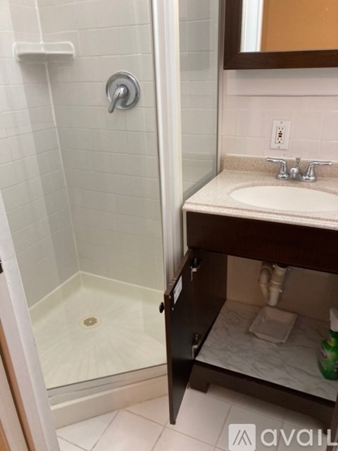 A bathroom with a glass shower stall and a sink with a mirror above it.