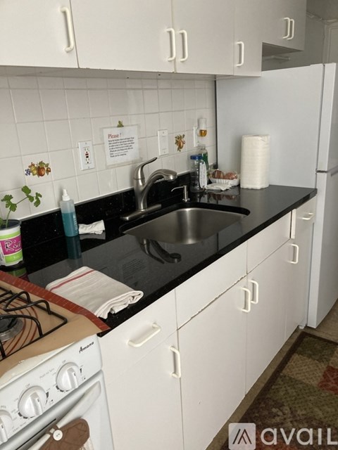 A kitchen with white cabinets and a black countertop.