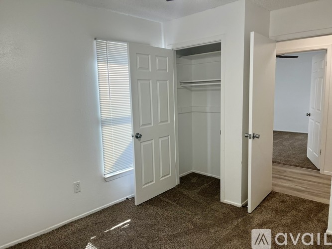 A small, empty bedroom with a white door and a carpeted floor.