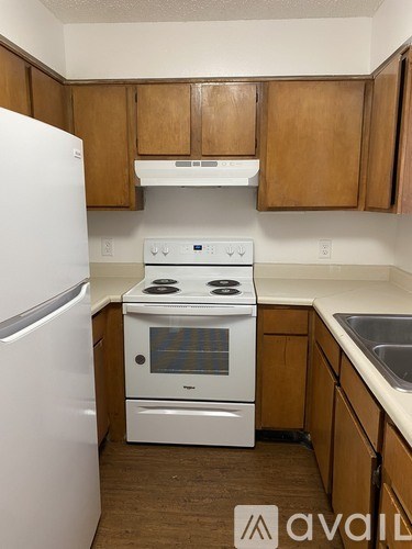 A kitchen with white appliances and wooden cabinets.