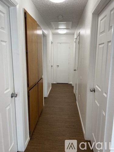 A hallway with white doors and brown flooring.