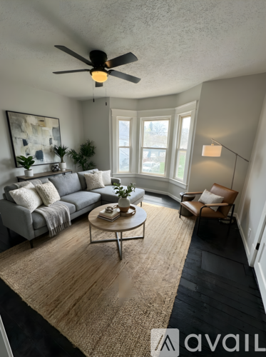 A living room with a grey couch, a coffee table, and a ceiling fan.