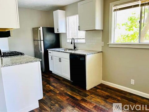 A kitchen with a black refrigerator and white cabinets.