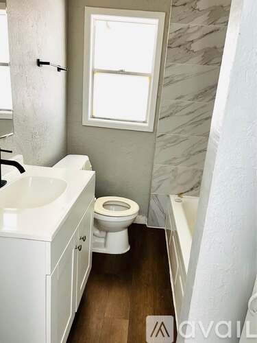 A bathroom with a toilet, sink, and a window.