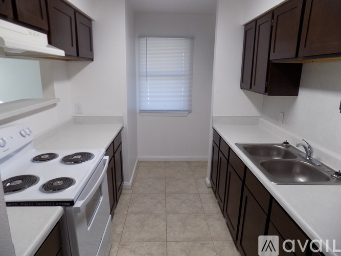 A kitchen with brown cabinets and a white sink.
