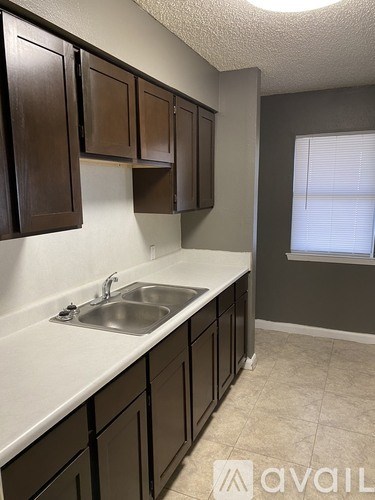 A kitchen with brown cabinets and a white sink.