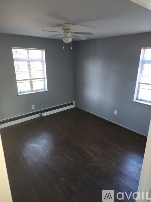 A room with a ceiling fan and two windows.