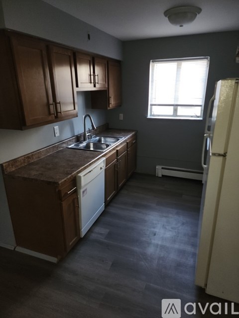 A kitchen with brown cabinets and a white dishwasher.