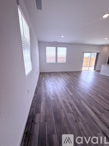 A spacious room with wooden flooring and white walls.
