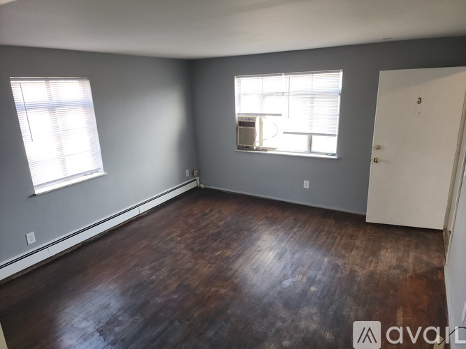 A room with wooden floors and a window with blinds.