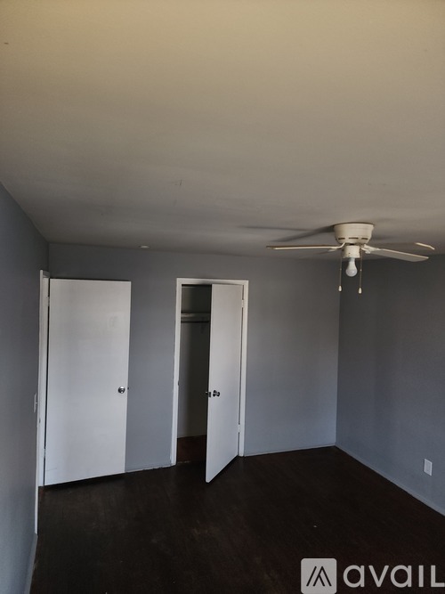 A room with a ceiling fan and three doors.