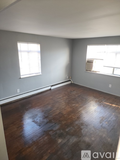 A room with wooden floors and two windows.