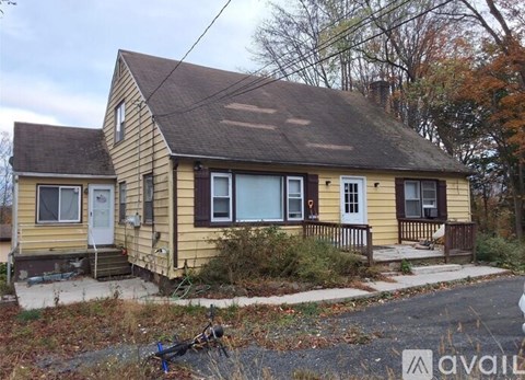 A small yellow house with a white door and windows.