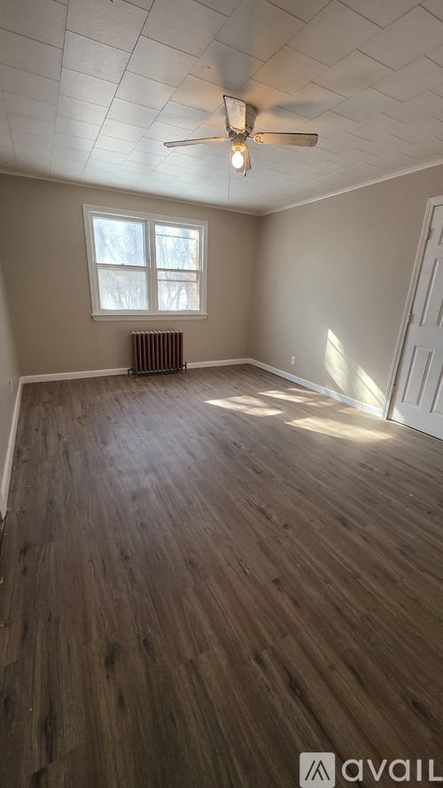 A room with wooden flooring and a ceiling fan.