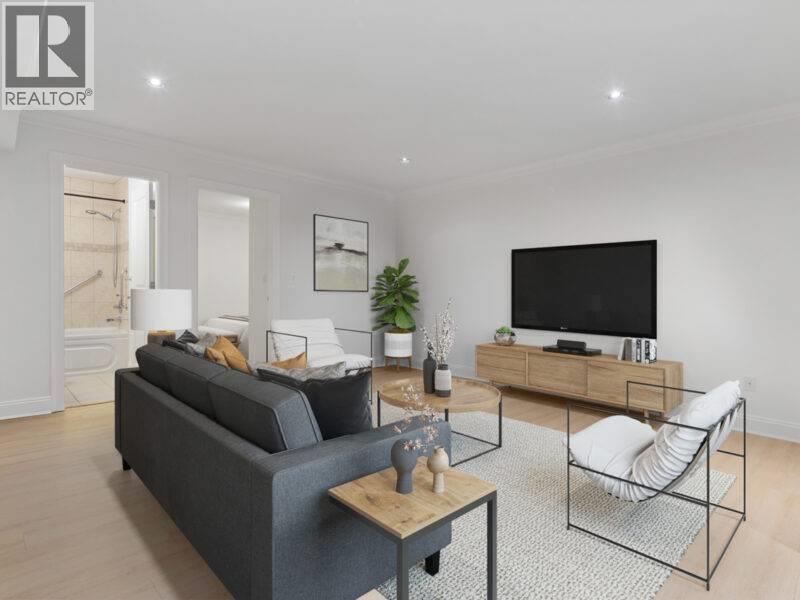 A living room with a grey sofa, a wooden coffee table, and a black television.