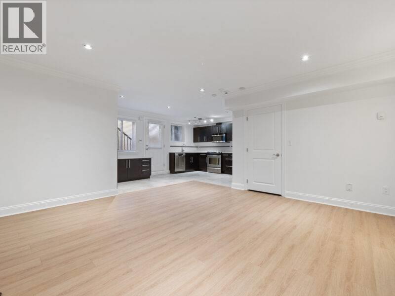 A spacious room with wooden flooring and white walls.
