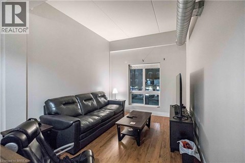 A living room with a black leather couch and a television.