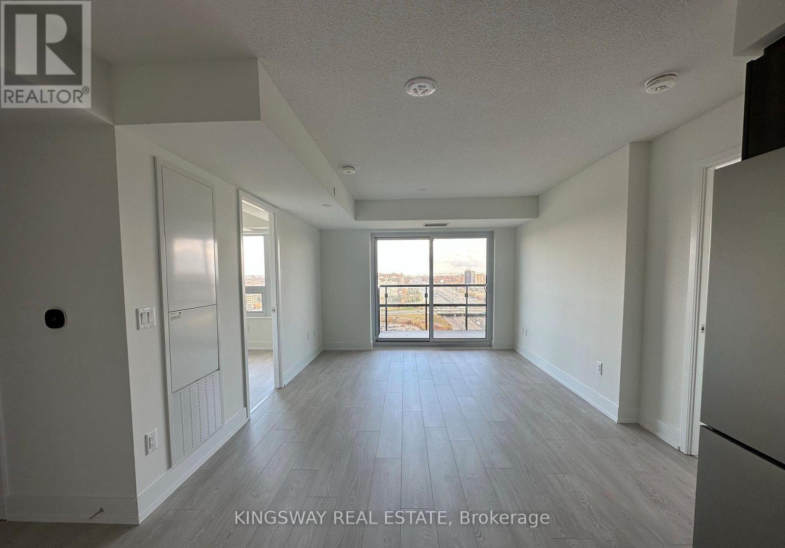 A spacious, empty room with a view of the outdoors through a large window.
