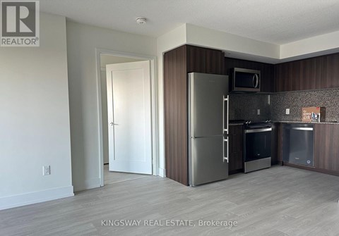 A kitchen with a refrigerator, microwave, and oven.
