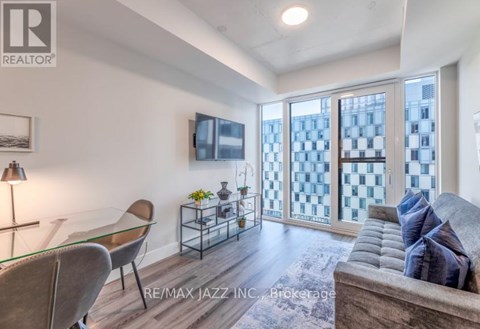 A living room with a glass table and a grey couch.