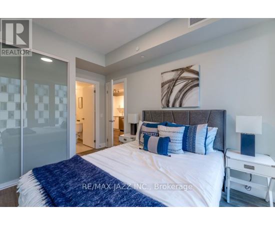 A bedroom with a bed, nightstand, and lamp.