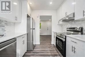 A white kitchen with a refrigerator and stove top oven.
